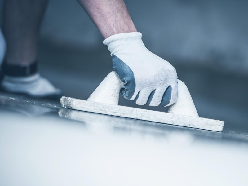 Finishing Concrete Home Floor. Closeup Photo. Hand with Finishing Tool. Construction Tool.